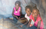 Children playing under mosquito net in RBM newsletter
